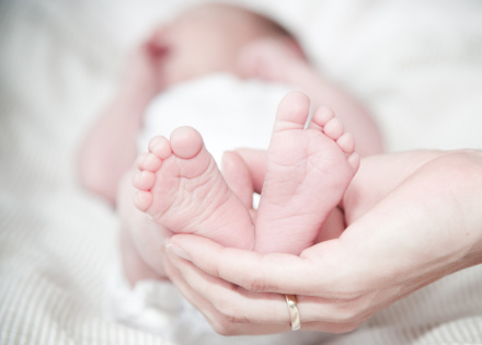 Newborn baby, with focus on a hand holding the babies feet